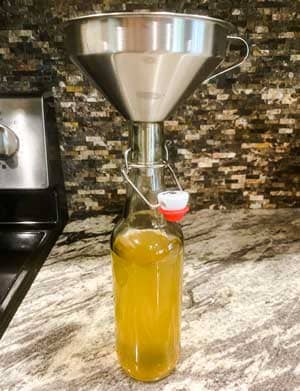 Pour kombucha into bottle with funnel