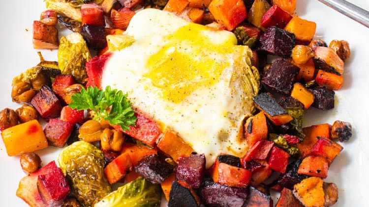 Roasted vegetables and one egg serve in a white bowl
