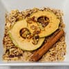 Oatmeal served in a white bowl topped with cinnamon stick and dried apple rings