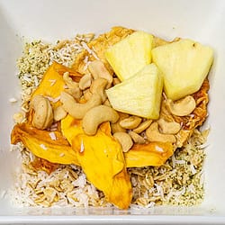 Oatmeal served in a white bowl topped with cashews and fruits