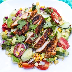 cajun chicken salad grilled and served with lot of vegetables on the white plate