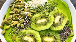 Green matcha smoothie bowl with kiwi, coconut, pumpkin seeds, and chia