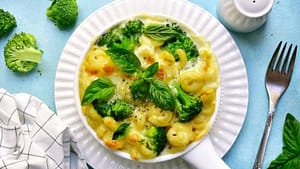 healthy mac and cheese served in the white plate with broccoli and basilico leaves on the top