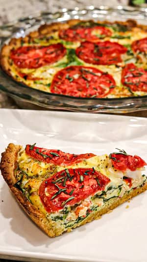 Slice of Tuscan Quiche with Garbanzo Bean Crust served in the white plate with Tuscan Quiche served in the glass bowl in the background