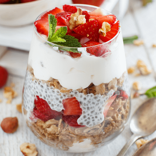 strawberry chia seed pudding layered with greek yogurt and oats in a glass