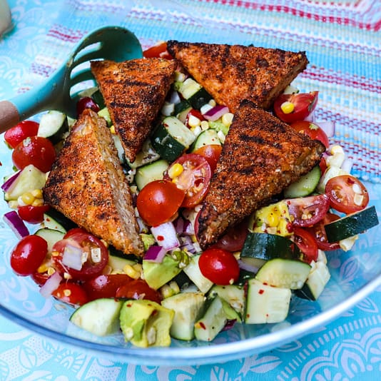 Cajun grilled chicken served in a glass plate with cherry potatoes, cucumbers and  onions