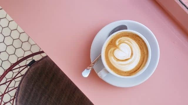 cup of coffe on a pink table, taken from above