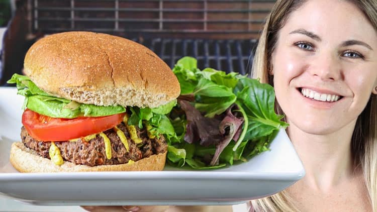 burger served on a white plate with some greens on the side, and Caitlin smiling