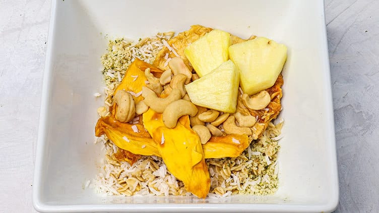 Oatmeal served in a white bowl topped with cashews and fruits