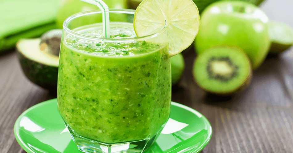 Green smoothie served in a glass with a straw and slice of a lime