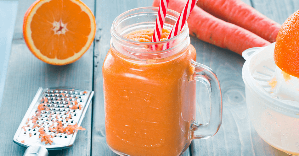 Orange smoothie served in a jar with two straws, and some carrots and oranges on the side