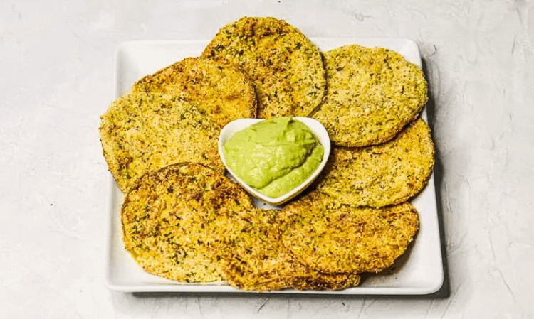 healthy fried green tomatoes served on a white plate with some guacamole in small white bowl