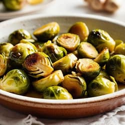 garlic ginger roasted brussel sprouts in a light dish with relevant ingredients in the background