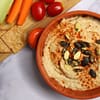 Heavenly Oil-free Hummus served in a ceramic bowl with different vegetables on the side