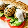 spinach turkey meatballs served in a sandwich with tomato, some greens, and alfredo sauce