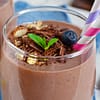 chocolate smoothie served ina glas wirg a colorful straw, and topped with shredded chocolate and blueberries