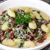 kale gnocci served in a white bowl and topped with some parsley and shredded cheese