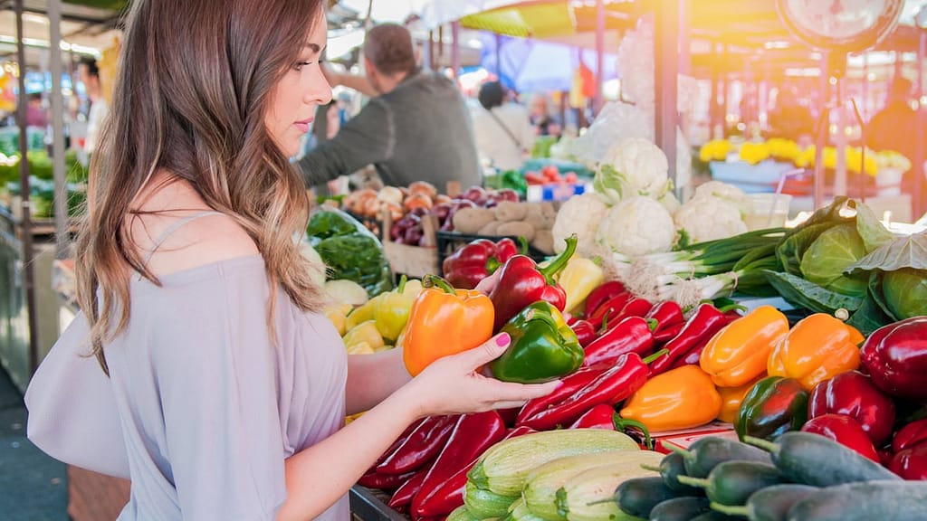 Girl shopping for produce at farmer's market with plant-based diet grocery list