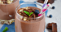 chocolate smoothie served ina glas wirg a colorful straw, and topped with shredded chocolate and blueberries