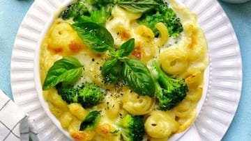 healthy mac and cheese served in the white plate with broccoli and basilico leaves on the top