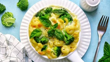 healthy mac and cheese served in the white plate with broccoli and basilico leaves on the top