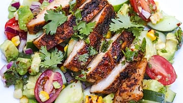cajun chicken salad grilled and served with lot of vegetables on the white plate