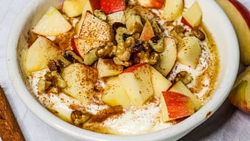 apple cinnamon yogurt served in a white bowl, topped with apples and nuts