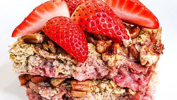 Baked oats topped with fresh strawberries served on a white plate