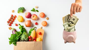 healthy ingredients in a paper bag and a piggy bank full of money