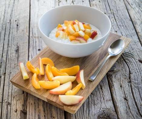 fruits served in a round white bowl with some fruits on the side