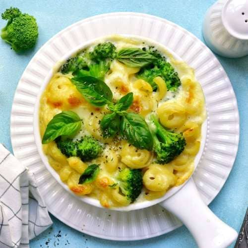 healthy mac and cheese served in the white plate with broccoli and basilico leaves on the top