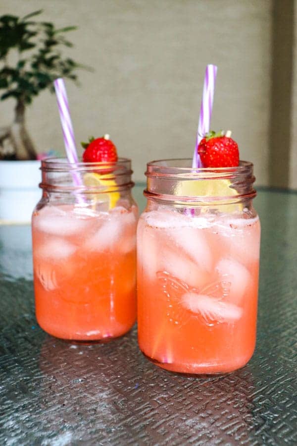 strawberry detox lemonade tall view on patio with bonsai tree in background