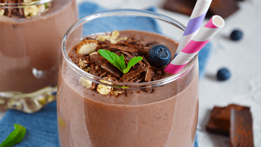 chocolate smoothie served ina glas wirg a colorful straw, and topped with shredded chocolate and blueberries