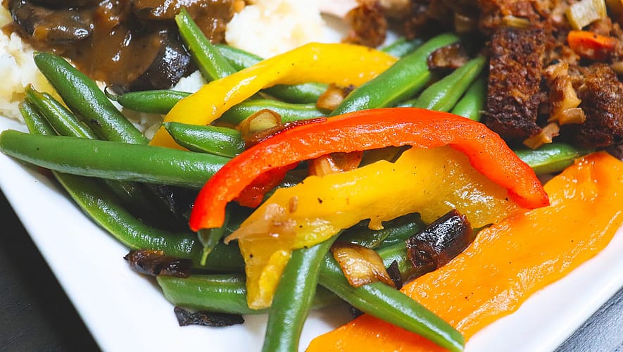 green beans with caramelized onions and peppers served on the white plate