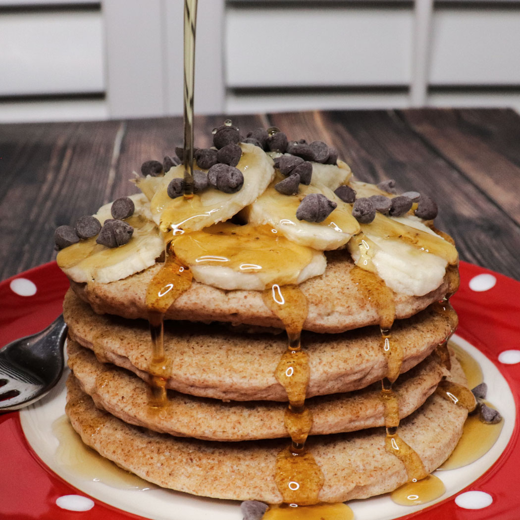 fluffy whole wheat vegan pancakes with maple syrup and chocolate chips on the plate